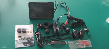 Motorcycle wireless navigation device components including screen, cables, mounts, and user manual on green surface.